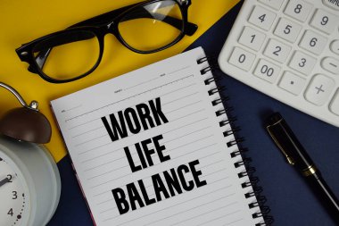 Not defterine yazılmış İş Hayatı Dengesi metni, hesap makinesi ve lacivert arkaplan üzerindeki alarm saati