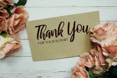 Tahta arka planda gül çiçeği buketi olan kağıt kartla teşekkür ederim.