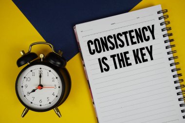 Tutarlılık, sarı arkaplanda alarmlı saat ile not defterine yazılmış anahtar metindir