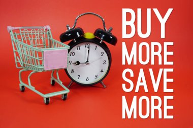 Tramvay alışveriş arabası ve kırmızı arkaplanda çalar saat ile daha fazla metin satın al