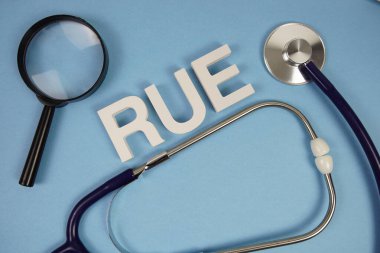 Sağ üst ekstremite alfabe harflerinin kısaltması. Mavi arka planda büyüteç ve steteskop var.