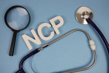 NCP, Hemşirelik Planı alfabesinin kısaltması. Mavi arka planda büyüteç ve steteskop var.