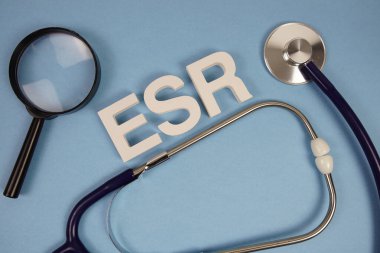 ESR Eritrosit Ayrıştırma Alfabe Oranı harfleri ve steteskop ve mavi arkaplanda büyüteç