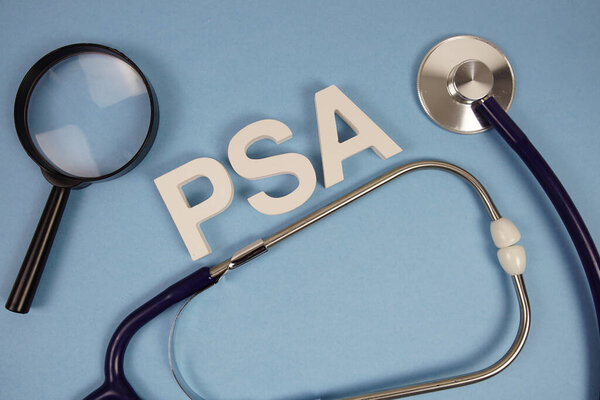 PSA abbreviation of Prostate Specific Antigen alphabet letters with magnifying glass and stethoscope on blue background
