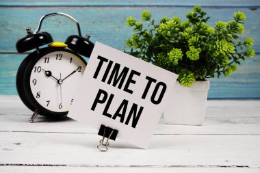 Tahta zemin üzerinde alarmlı saat yazılı kağıt kart üzerine yazılmış metni planlama zamanı