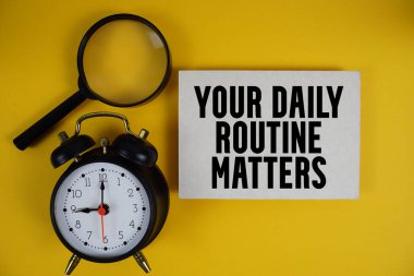 Günlük rutininiz, kağıda yazılan, büyüteç ve sarı zemin üzerindeki alarm saati ile ilgili.