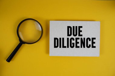 Sarı arkaplanda büyüteçle kağıda yazılmış Diligence metni