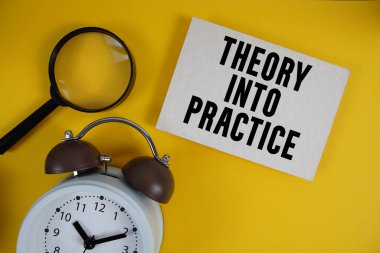 Kağıda yazılan, büyüteç ve sarı zemin üzerindeki alarm saati teorisi.