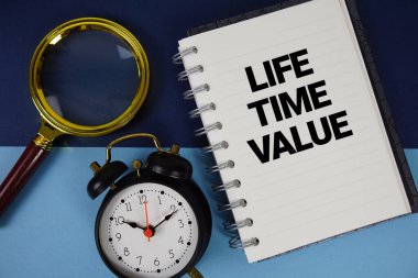 Not defteri kağıdına büyüteç ve alarm saati ile yazılmış Yaşam Saati Değeri metni