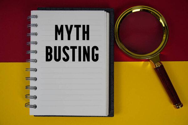 Myth Busting text written on notebook paper with magnifying glass