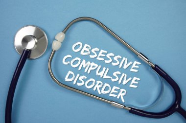Mavi arkaplanda steteskoplu takıntılı kompülsif bozukluk metni