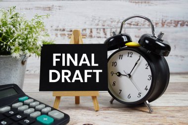 Ahşap zemin üzerinde alarm saati ve hesap makinesi olan son taslak metin