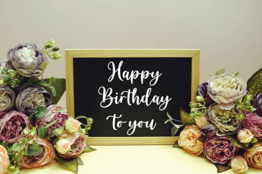 Mutlu yıllar sana. Sarı arkaplanda çiçek süslemesi olan kısa mesaj.