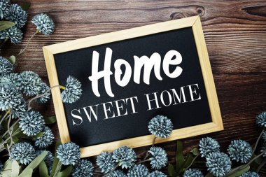 Tahtadaki Home Sweet Home metni ahşap arka planda çiçek süslemesi