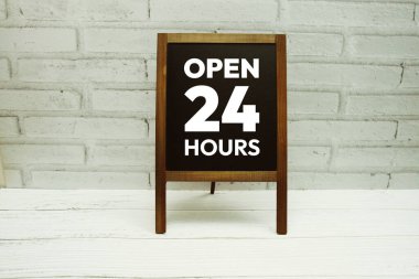 Beyaz tuğla zemin üzerinde karatahta ile 24 Saat işareti aç