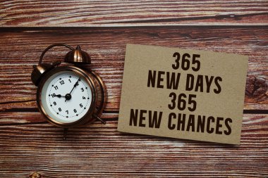 Tahta zemin üzerinde alarm saati olan 365 Yeni Gün Yeni Şanslar metni