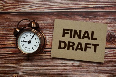 Ahşap zemin üzerinde alarm saati olan son taslak metin