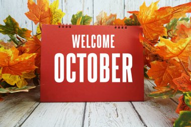 Ahşap zemin üzerine akçaağaç yaprağı süslenmiş ekim ayına hoş geldiniz metni