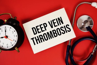 Kağıt üzerinde steteskop ve kırmızı zemin üzerinde alarm saati ile yazılmış Derin Damar Trombozu metni