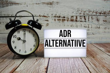 Aydınlatma kutusunda ahşap zemin üzerinde alarm saati olan ADR Alternatif metin