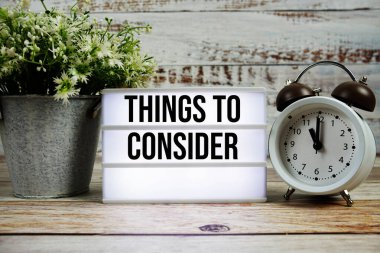 Işık kutusunda, ahşap zemin üzerinde alarmlı saat olan metinler düşünülecek şeyler