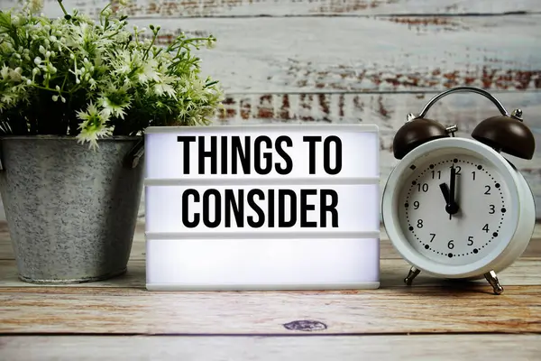 Işık kutusunda, ahşap zemin üzerinde alarmlı saat olan metinler düşünülecek şeyler