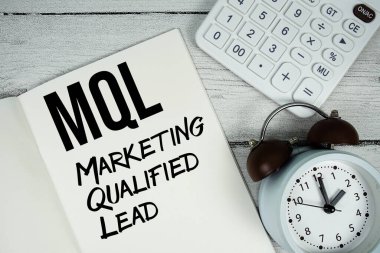 MQL Pazarlama Kalifiye Kağıt defter üzerinde kurşun metin Alarm saati ve ahşap zemin üzerinde hesap makinesi ile