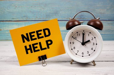 Tahta zemin üzerinde alarm saati olan kağıt üzerine yazılmış yardım metnine ihtiyaç var