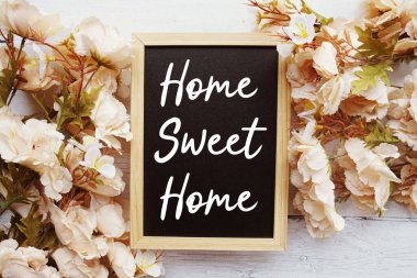 Ahşap arka planda çiçek süslemeli Home Sweet Home metni