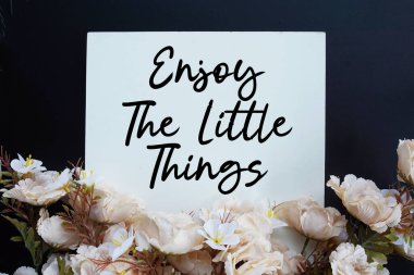 Siyah arka planda çiçek süslemesi olan Küçük Şeyler 'in tadını çıkarın.