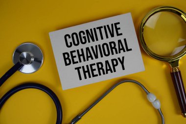 Bilişsel Davranış Terapisi (CBT) metni kağıt üzerinde stetoskop ve büyüteç düz sarı zemin üzerinde yatıyordu