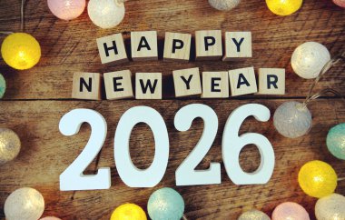 Yeni yılınız kutlu olsun. Ahşap zemin üzerinde LED pamuk topları olan alfabe harfleri.