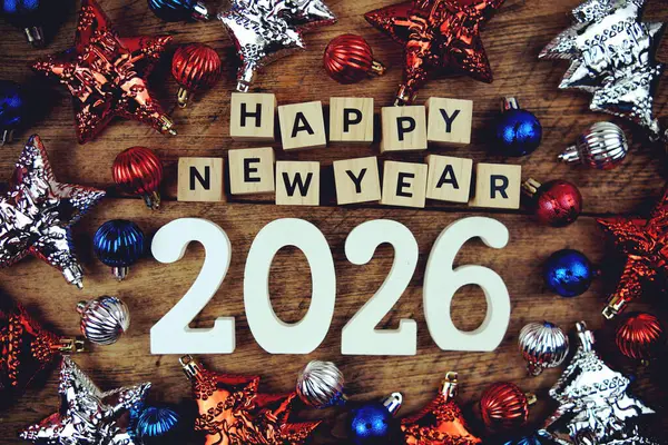 Yeni Yıl 2026 alfabe harfleri ve ahşap arka planda Noel süslemeleri.