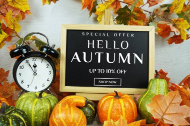 Sonbahar İndirimi% 10 alarm saati ve ahşap arka planda akçaağaç yaprağı süslemesi içeren metin