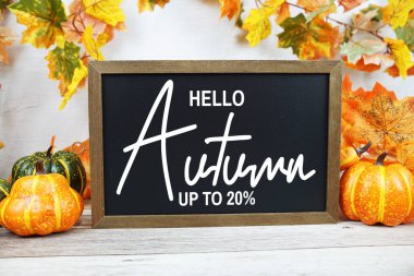 Sonbahar İndirimi% 20 alarm saati ve ahşap arka planda akçaağaç yaprağı süslemesi içeren metin