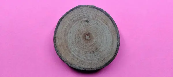 Wooden circle on pink background. Top view with copy space.