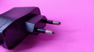 Black power plug on a pink background. Copy space for text. clipart