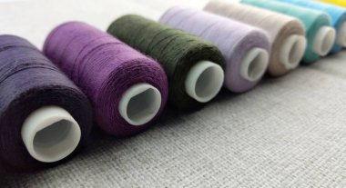 Beyaz kumaş arka planında çok renkli iplikler.