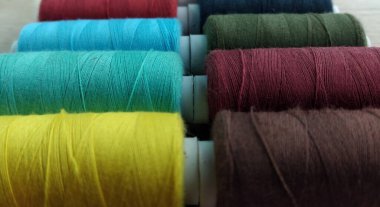 Beyaz kumaş arka planında çok renkli iplikler.