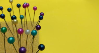 Sarı arka planda renkli raptiyeler ve mezuralar.