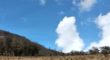 Dağların panoramik manzarası ve mavi gökyüzündeki bulutlar