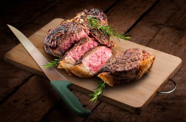 Fiorentina T-Bone bifteği dikdörtgen ahşap kesim tahtası ve tahta arka planda izole edilmiş bıçak.