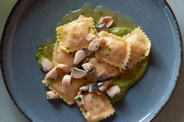 stock image Top view of Ravioli with Genoese pesto sauce and swordfish cubes in blue plate