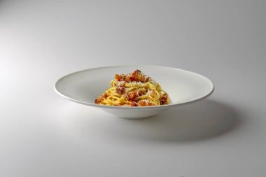 Spagetti carbonara ile modern tasarımı olan çorba tabağı ve beyaz arka planda izole edilmiş rendelenmiş peynir.