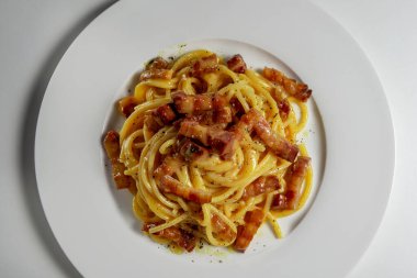Beyaz arka planda spagetti carbonara ile beyaz yuvarlak tabak üst görünüm