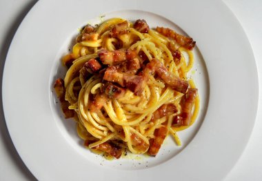 Beyaz arka planda spagetti carbonara ile beyaz yuvarlak tabak üst görünüm