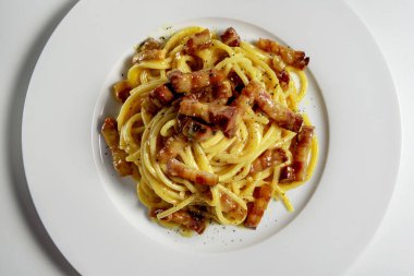 Beyaz arka planda spagetti carbonara ile beyaz yuvarlak tabak üst görünüm