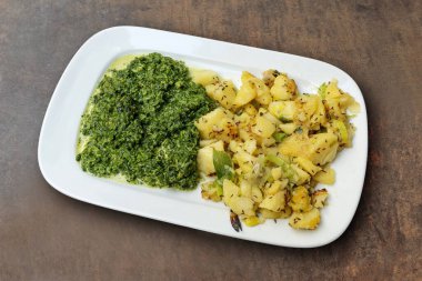 Kırpılmış ıspanaklı, patatesli ve kabataslak arkaplanda taze soğanlı dikdörtgen yemek.