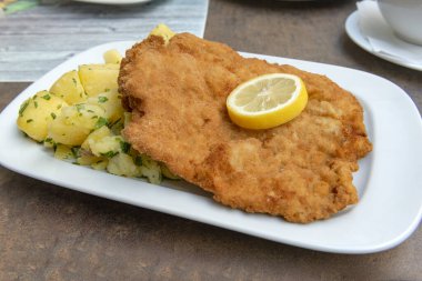 Schnitzel Classisc Viennese Veal Cutlet with potato salad and lemon slices on rough table clipart