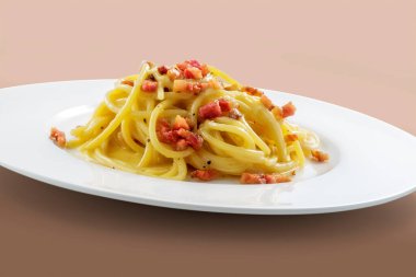 Kahverengi arka planda bir tabak spagetti carbonara.